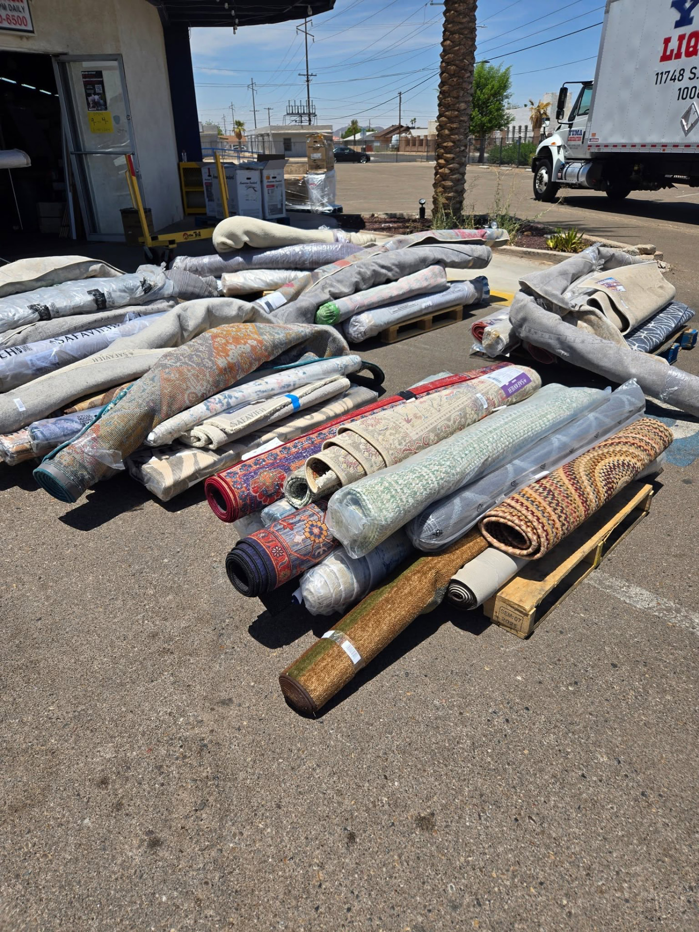 Rolled area rugs stacked on pallets outside the store