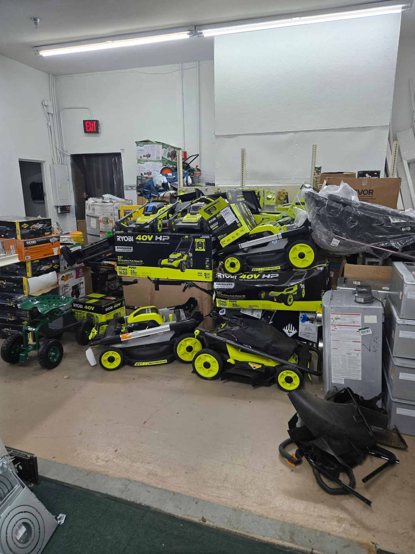 Rows of Ryobi push mowers and yard equipment in the warehouse